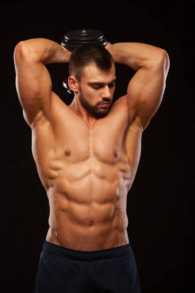 Güçlü adam egzersizleri triceps bir dumbbell ile yapmak. Atış eğitim eller yukarı kapatın. Onun gövde altı ile gösterilen fitness modeli bohça abs. boşaltmak siyah zemin üzerine izole — Stok fotoğraf
