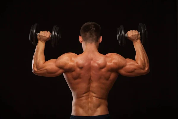 Musculoso culturista modelo masculino haciendo ejercicios con pesas, volvió. Aislado sobre fondo negro con copyspace — Foto de Stock