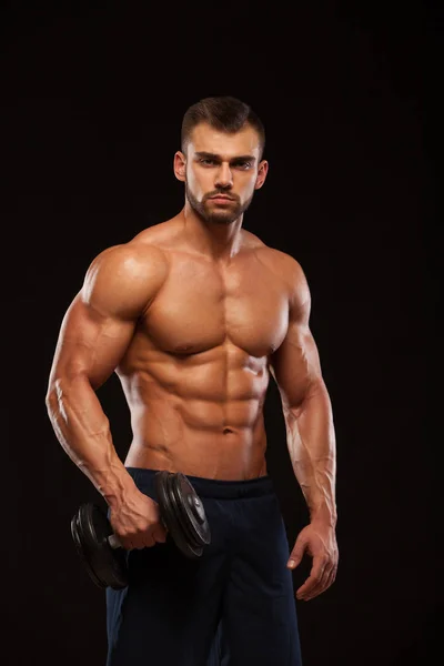 Yakışıklı güç atletik erkek dumbbell ile güvenle iple çekiyor. Altı paket, mükemmel abs, omuzlar, pazı, triceps ve göğüs ile güçlü vücut geliştirmeci izole siyah zemin üzerine
