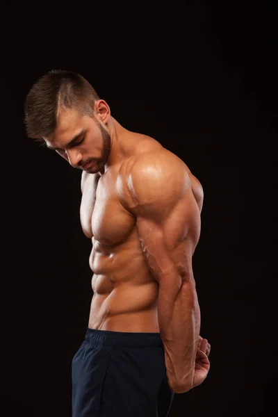 Homem Atlético Forte Modelo Fitness mostrando suas costas perfeitas isoladas em fundo preto com copyspace — Fotografia de Stock