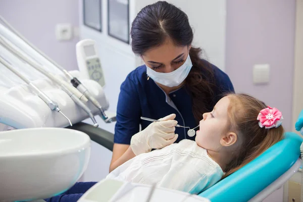 Dentista feminino em máscara trata dentes menina — Fotografia de Stock