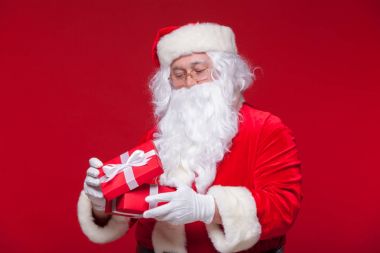 Noel. Fotoğraf Noel xmas hediye veriyor ve kamera, kırmızı bir arka plan üzerinde bakıyorsun baba