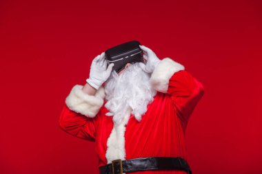 Santa Claus wearing virtual reality goggles, on a red background. Christmas clipart