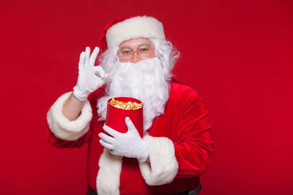 Traditionelle Weihnachtsmann vor dem Fernseher, essen Popcorn. Weihnachten. roter Hintergrund. Emotionen fürchten Überraschung — Stockfoto