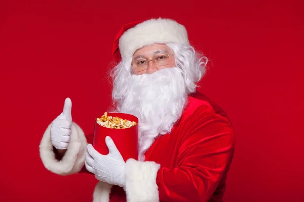 Père Noël traditionnel regardant la télé, mangeant du pop-corn. Noël. Fond rouge. émotions peur surprise — Photo