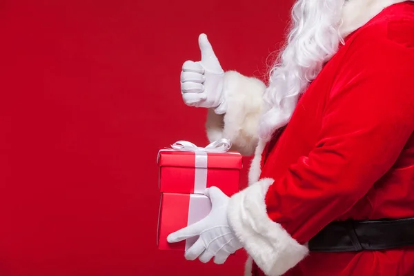 Weihnachtsfoto von weihnachtsmann handschuh hand mit roter geschenkbox. Daumen hoch — Stockfoto