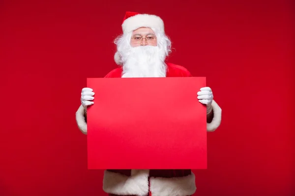 Weihnachtsmann zeigt auf leeres Werbebanner auf rotem Hintergrund mit rotem Blatt — Stockfoto