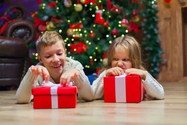 Niños yacen cerca de regalo de Navidad en frente del árbol — Foto de Stock