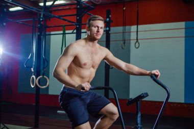 Spor salonunda egzersiz bisikleti kullanan genç adam uygun. Kardiyo egzersiz spor eğitim çapraz için hava bisiklet kullanarak fitness erkek.