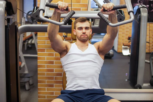 체육관에서 운동하는 남자. 수직 벤치 인쇄기 위에서 가슴 운동을 하는 건강 한 운동 선수 — 스톡 사진
