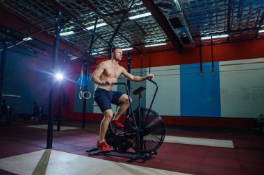 Spor salonunda egzersiz bisikleti kullanan genç adam uygun. Kardiyo egzersiz spor eğitim çapraz için hava bisiklet kullanarak fitness erkek.