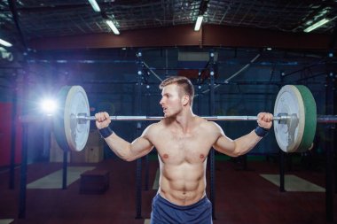 Yakışıklı bir atlet portresi. Atlet halter başının üzerine yükseltir. çekim koyu tonda. Çapraz uygun stil, deadlift