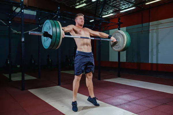 Muskulöser Fitness-Mann bereitet sich darauf vor, in einem modernen Fitness-Center eine Langhantel über den Kopf zu heben.. — Stockfoto