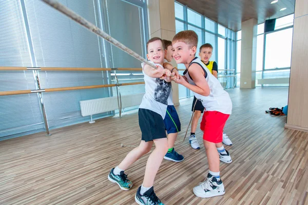 Kinderen en recreatie, groep gelukkig multi-etnisch school kinderen spelen touwtrekken met touw in sportschool — Stockfoto