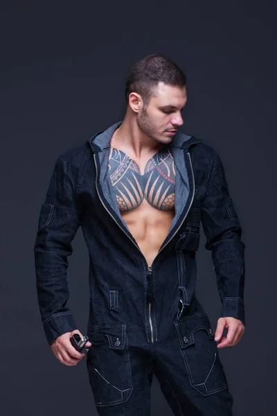 Mannen med en muskulös överkropp med tatueringar på den mörka bakgrunden — Stockfoto
