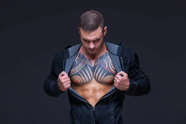 Der Mann mit muskulösem Oberkörper mit Tätowierungen auf dunklem Hintergrund — Stockfoto