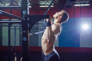 Atlet kas fitness erkek modeli yatay çubuğu bir spor salonunda yanaşıyor. Çapraz uygun stil