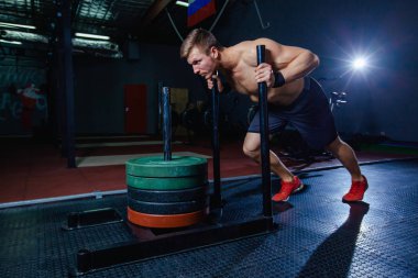 kızak itme adam spor salonunda ağırlık egzersiz egzersiz bastırıyor. Çapraz uygun stil