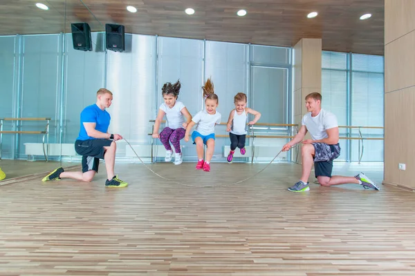 Leende glada barn i skolåldern som spelar tillsammans med hoppa rep i gymmet. Barn på fysisk fostran lektion i skola gym. — Stockfoto