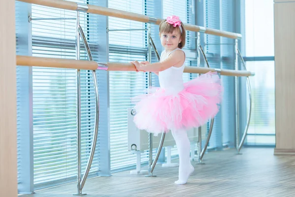 Uma bailarina com um tutu cor-de-rosa. Criança adorável dançando balé clássico em um estúdio branco. As crianças dançam. Crianças a actuar. Jovem dançarina talentosa numa aula. Criança pré-escolar tendo aulas de arte . — Fotografia de Stock