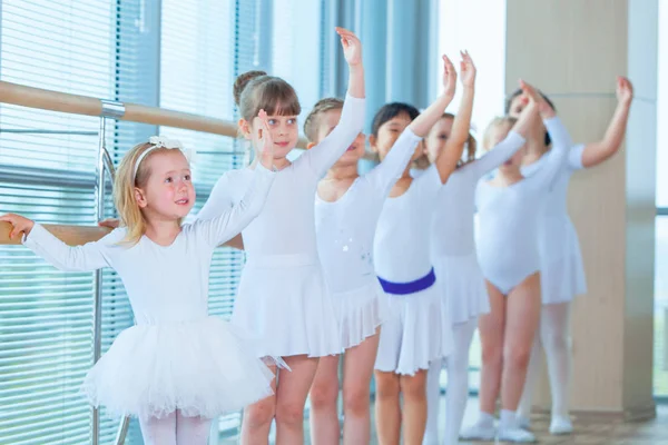 Jovens bailarinas ensaiando na aula de balé. Eles realizam diferentes exercícios coreográficos. Eles estão em diferentes posições perto do ballet barr . — Fotografia de Stock