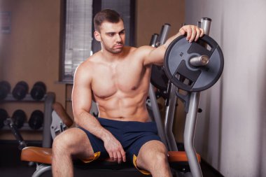 Zalim atletik adam göğüs presinde kaslarını şişiriyor.