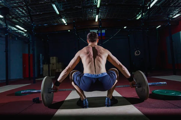 Muskulöser Fitness-Mann bereitet sich darauf vor, in einem modernen Fitness-Center eine Langhantel über den Kopf zu heben.. — Stockfoto