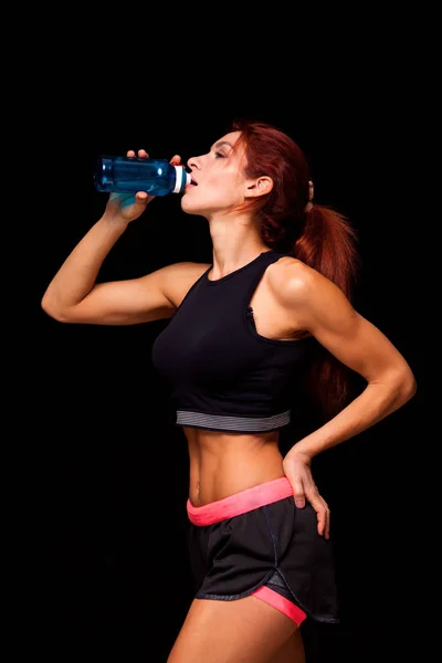 Hermosa mujer con botella de agua. Cuerpo femenino perfecto aislado sobre fondo negro — Foto de Stock