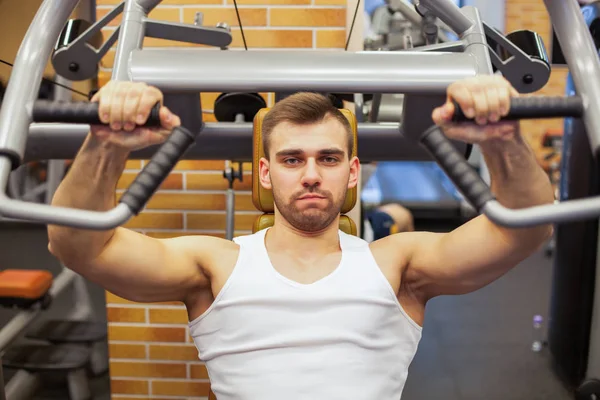 Man exercising at gym. Fitness athlete doing chest exercises on vertical bench press machine