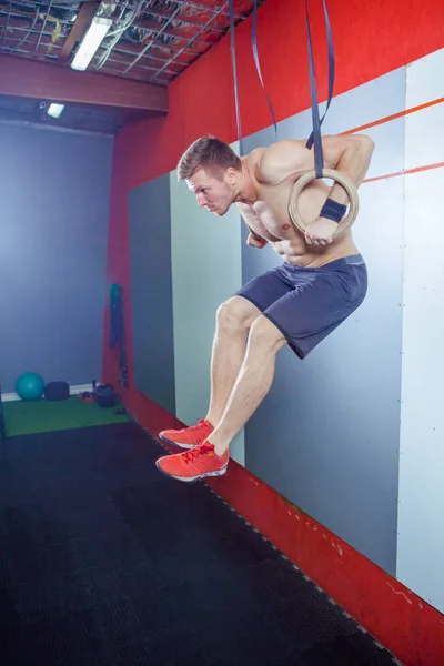 Muscle-up motion ung man gör intensiv cross fit träning på gymmet på Gymnastringar. — Stockfoto