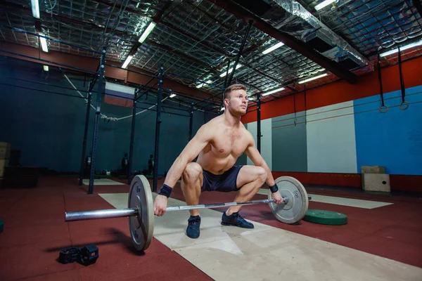 Muskulöser Fitness-Mann bereitet sich darauf vor, in einem modernen Fitness-Center eine Langhantel über den Kopf zu heben.. — Stockfoto