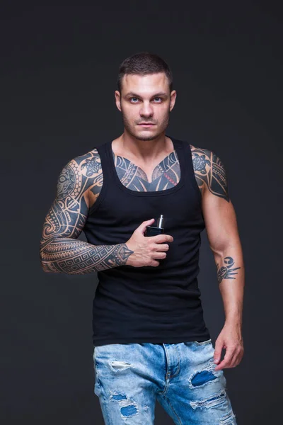 Vaper. El hombre con un torso muscular con tatuajes fuma un cigarrillo electrónico en el fondo oscuro — Foto de Stock