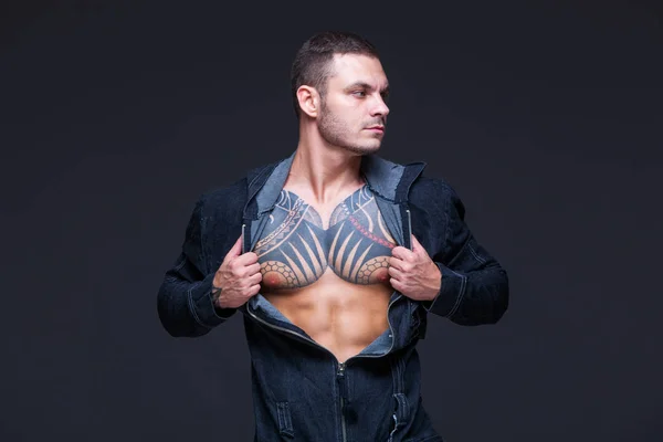 El hombre con un torso muscular con tatuajes en el fondo oscuro —  Fotos de Stock