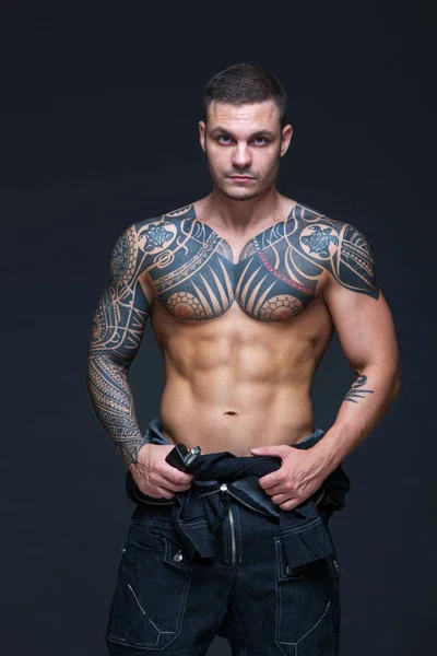 El hombre con un torso desnudo muscular con tatuajes en el fondo oscuro. ABS —  Fotos de Stock