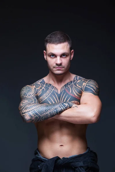 Mannen med en muskulös nakna torso med tatueringar på den mörka bakgrunden. ABS — Stockfoto