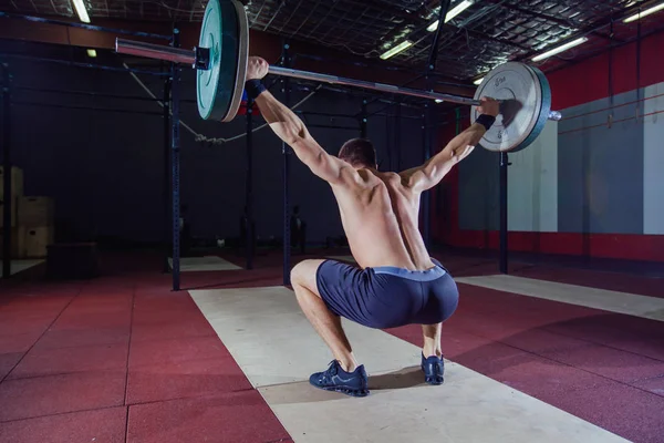 Sportlicher Mann, der mit einer schweren Langhantel über Kopf Kniebeugen im Fitnessstudio Crossfit Crossfit Leistungssportler Active Lifestyle Gewichtheben Bodybuilder durchführt. Crossfit-Stil, Kreuzheben — Stockfoto