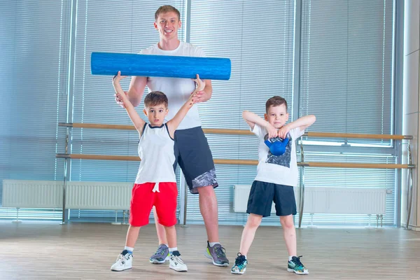 Groep kinderen doen kinderen Turnen in sportschool met leraar. Gelukkige sportieve kinderen in sportschool. Foam roller — Stockfoto