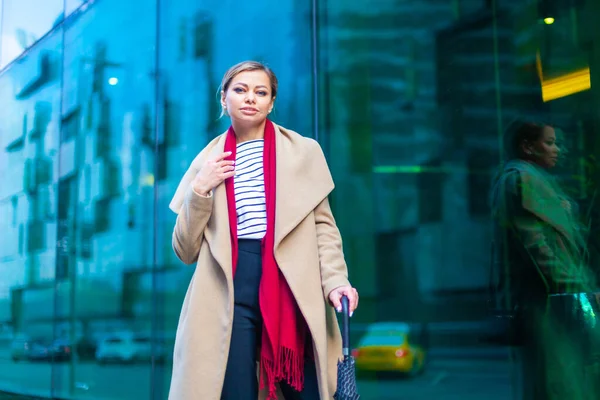 Estilo de vida ao ar livre retrato de moda da menina morena deslumbrante. Caminhando na rua da cidade. Vou às compras. Vestindo elegante casaco branco equipado, lenço de pescoço vermelho, bengala guarda-chuva preto. Mulher de negócios . — Fotografia de Stock