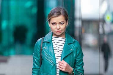 Açık havada yaşayan esmer bir kızın moda portresi. Şehir caddesinde yürüyorum. Alışverişe. Şık turkuaz yeşil bir ceket giymişti. Kapatın. İş kadını.
