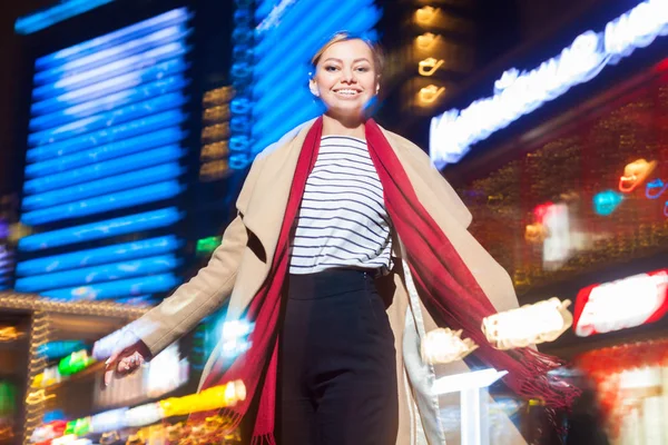 Vrolijk meisje in trendy kleding opgewonden met nachtlampjes in Big City, mooie brunette vrouw blij over het doorbrengen van 's avonds vrije tijd in het centrum met neon verlichting. — Stockfoto