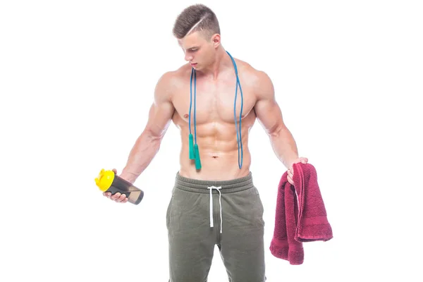 Gespierde man overslaan touw. Portret van gespierde jonge man met springen touw drinkwater met rode handdoek over de nek, geïsoleerd op witte achtergrond. Sterke atletische man-fitness model toont zijn — Stockfoto