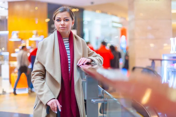 In het winkelcentrum lifestyle mode portret van een prachtig brunette meisje. Lopend in het winkelcentrum. Winkelen. Draag stijlvolle witte jas, rode neksjaal, zwarte paraplustok. Zakelijke vrouw. — Stockfoto