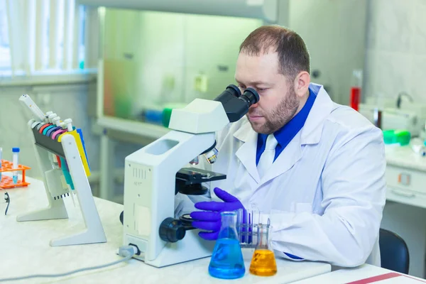 Especialista mirando a través del microscopio realizando investigación científica en un laboratorio. Prueba de orina . —  Fotos de Stock