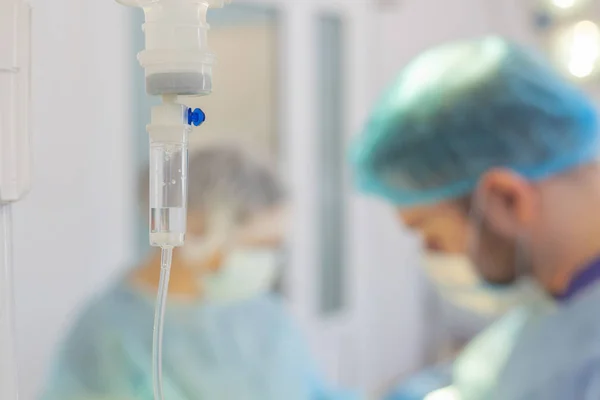 Nemocnice. Chirurg operuje na operačním sále. Kapátko na rozmazané pozadí s operačními lékaři — Stock fotografie