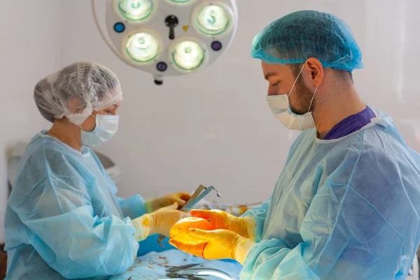 Sjukhuset. Kirurgen opererar i operationssalen. Läkaren och sjuksköterskan desinficerar implantatet innan det sätts in under bröstförstoring.. — Stockfoto