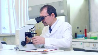 Kimyager. Bir bilim adamı bilimsel bir laboratuvarda deneyler yapar. Mikroskop kullanarak araştırma yapıyor. Evreka. - Zafer. Yeni bir keşif. Mutlu bilim adamı.