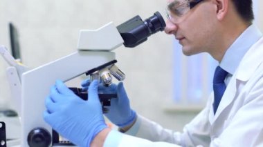 Bilimadamı bir tıp laboratuarında mikroskop altında bilimsel araştırmalar yapıyor..