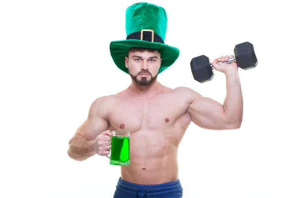 Ημέρα του Αγίου Πατρικίου. Ένας μυώδης άντρας με πράσινο καπέλο κρατάει μια κούπα μπύρα, και ένα μαύρο βαράκι. Απομονωμένο λευκό φόντο. Αμπς.. — Φωτογραφία Αρχείου