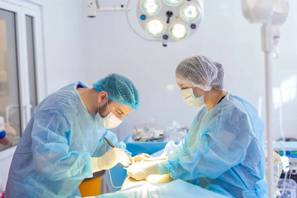 Sjukhuset. Kirurgen opererar i operationssalen. Tillhandahålla medicinsk hjälp till patienten. — Stockfoto
