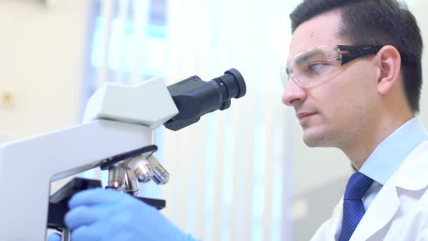 Lo scienziato svolge la ricerca scientifica guardando attraverso il microscopio in un laboratorio medico . — Video Stock